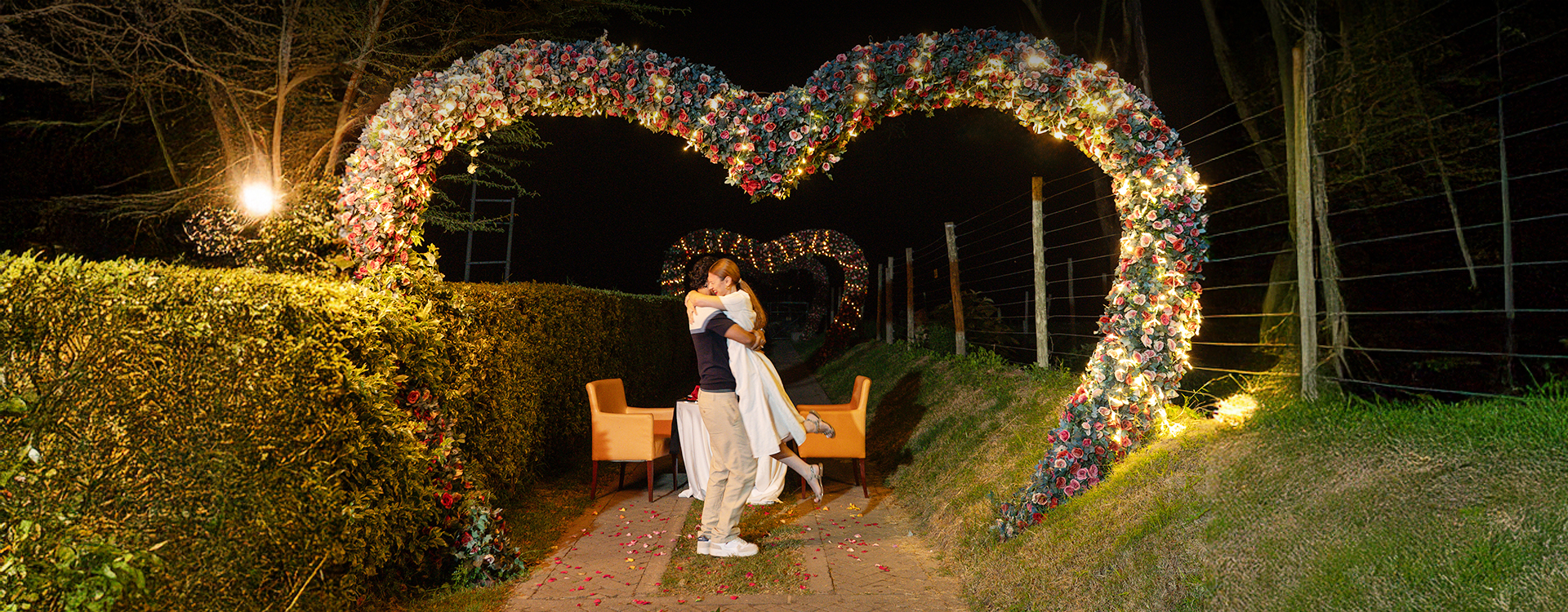 Couple under heart-shaped light setup at night
